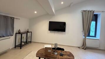 A living room with a flat-screen TV mounted on the wall, a wooden coffee table, and a patterned rug.