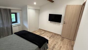 A bedroom with a bed, a television, a wardrobe, and a window.