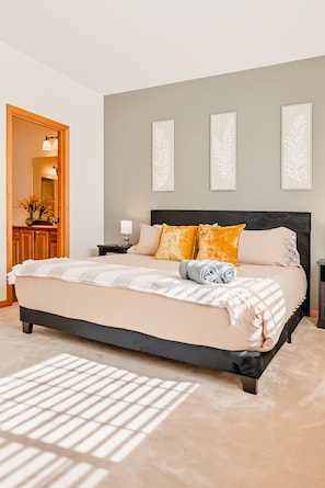 A bedroom with a large bed, a nightstand, a mirror, and three wall-mounted light fixtures.