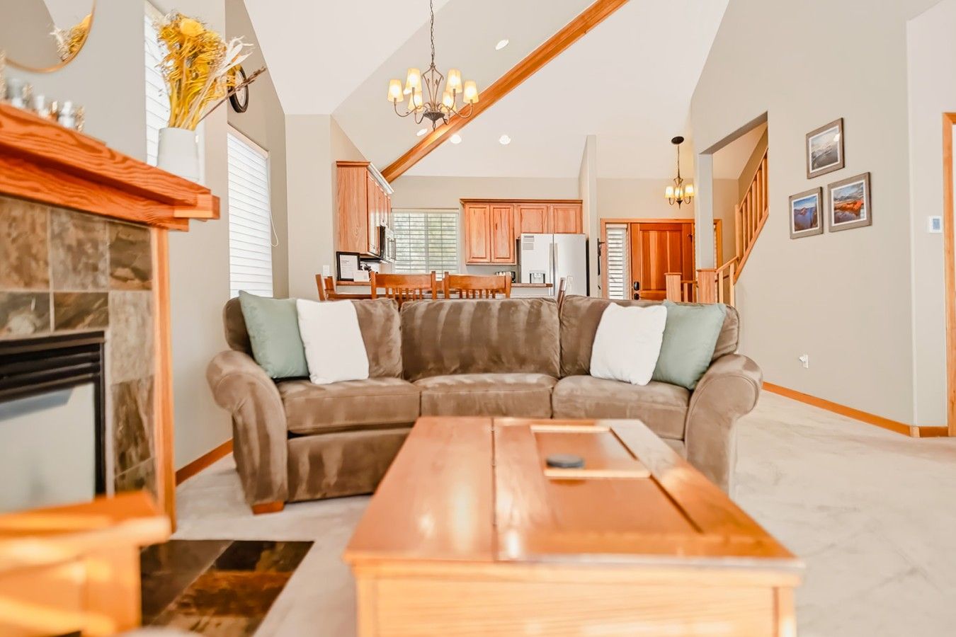 Un salon spacieux avec un canapé d’angle, une table basse en bois et une cheminée.