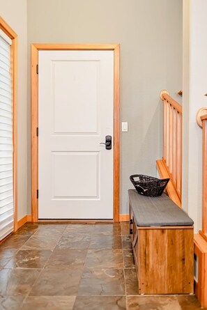 A hallway with a double door, a bench, and a wooden handrail.