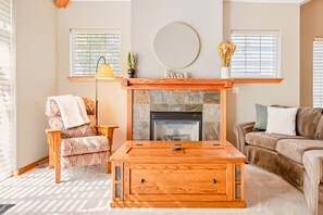 A cozy living room with a fireplace, a sofa, a coffee table, and a lamp.