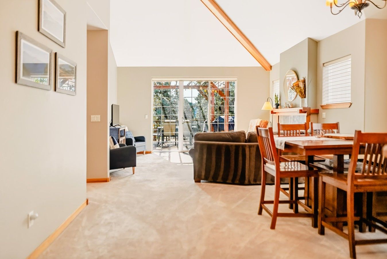 Uma sala espaçosa com mesa de jantar, cadeiras e sofá. Há uma grande janela que oferece vista para o exterior.