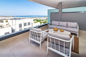 A balcony with a sofa and chairs, a small table with bowls, and a view of the city and sea. - LME101A- Lovley Apartment with stunning views (Estepona)