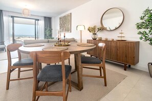 A dining area with a round wooden table, four chairs, a modern lamp, a decorative mirror, and a wooden cabinet. - LME101A- Lovley Apartment with stunning views (Estepona)