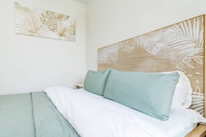 A bed with a wooden headboard, a green pillow, and white bedding. - LMe2BA- Cozy ground floor flat in luxury resort (Estepona)