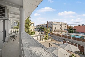 A balcony with a view of a swimming pool, a parked motorcycle, and a row of umbrellas. - Apartment 'Angel' with Sea View, Wi-Fi and Air Conditioning (Σιδάρι)