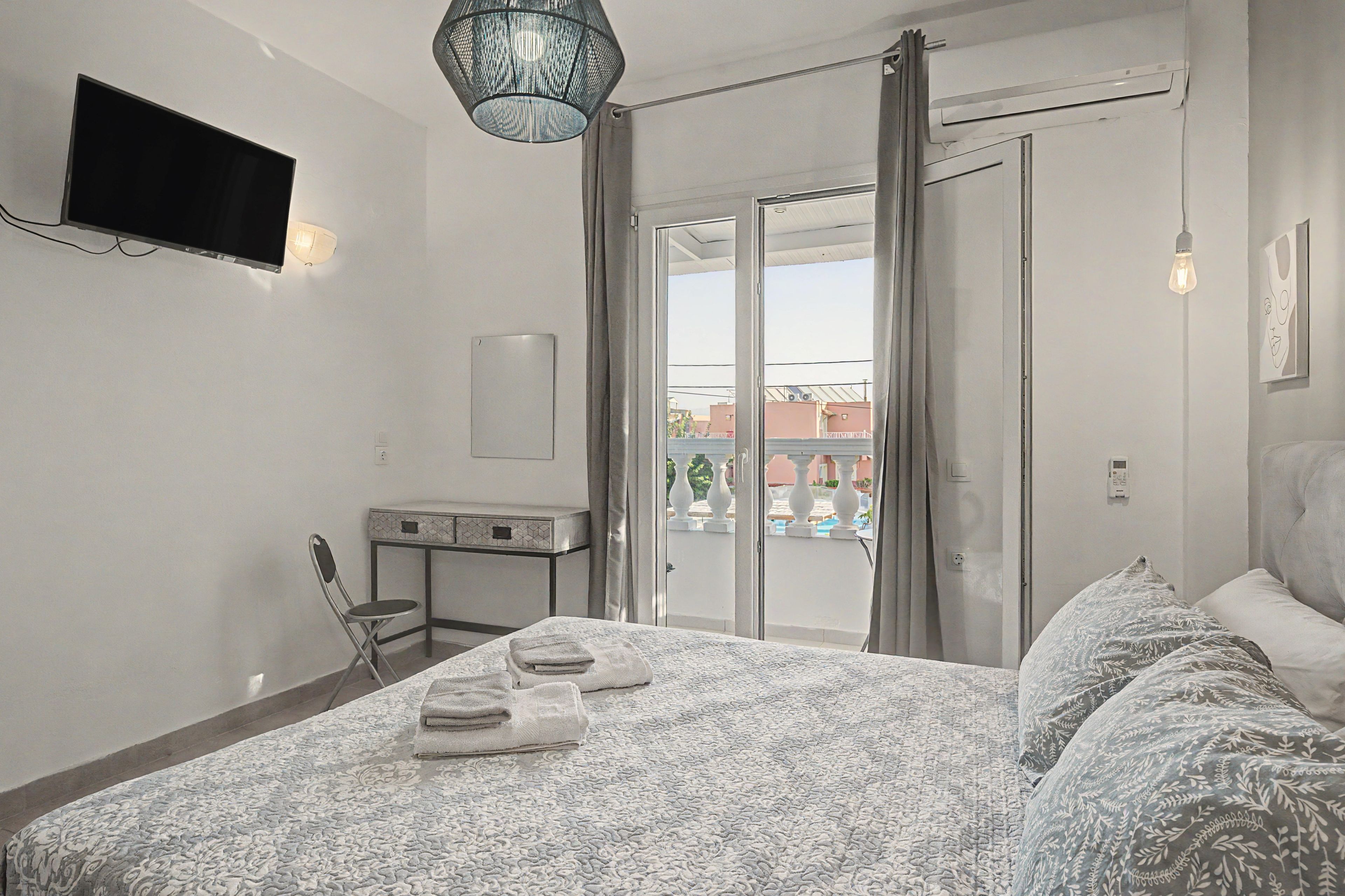 Een slaapkamer met een bed, een flatscreen televisie, een bureau en een stoel.