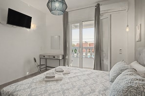 A bedroom with a bed, a flat-screen TV, a desk, and a chair. - Apartment 'Angel' with Sea View, Wi-Fi and Air Conditioning (Σιδάρι)