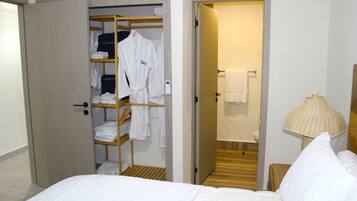 Ein Hotelzimmer mit einem Bett, einem Schrank mit Bademänteln, einem Badezimmer mit Handtuchhalter und einer Nachttischlampe.