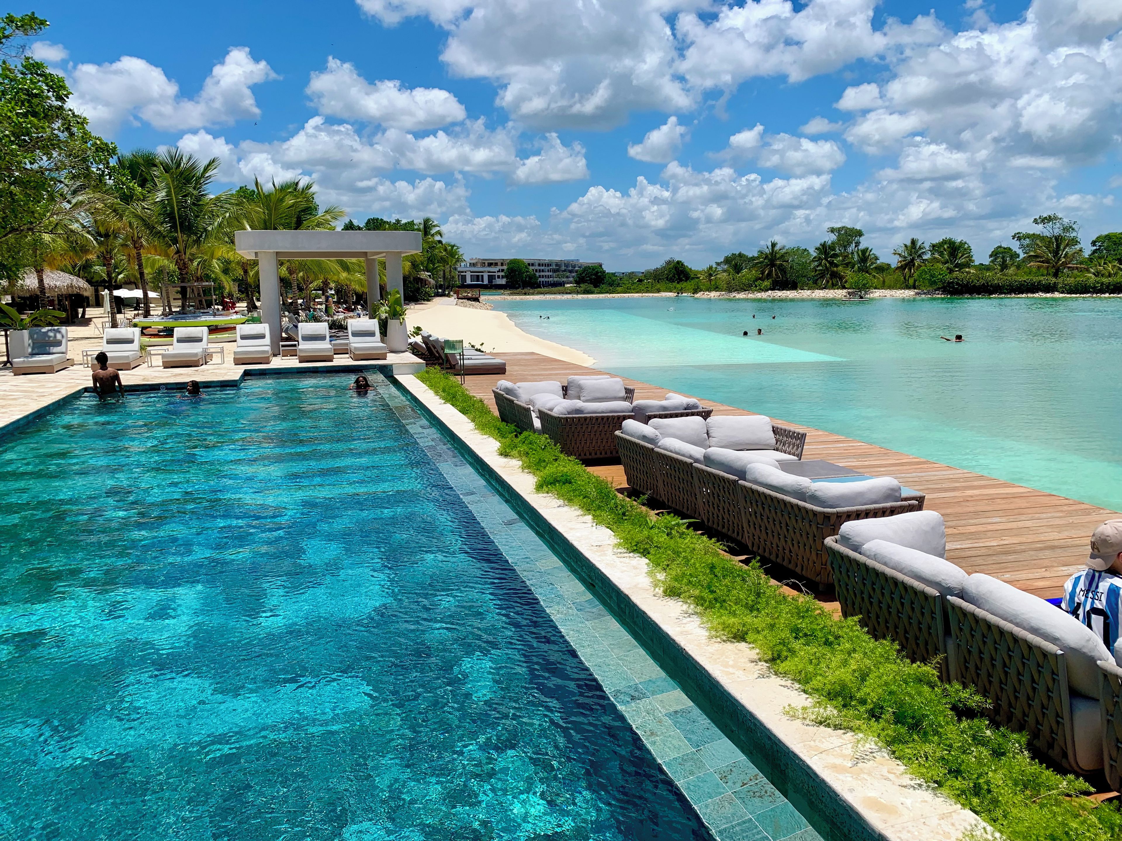 Une piscine avec des chaises longues et une terrasse en bois donnant sur une plage.