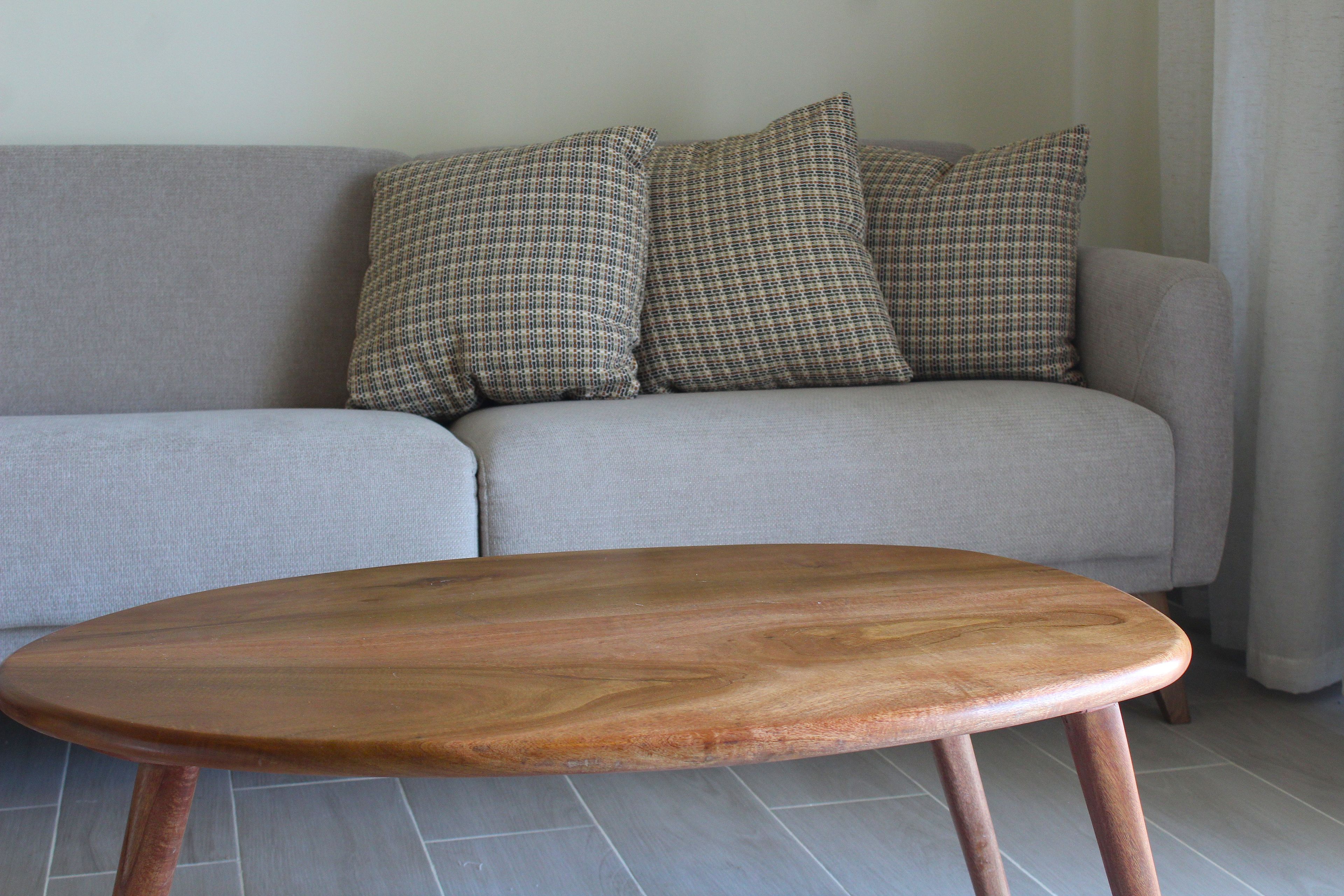 A grey sofa with patterned cushions and a wooden coffee table with metal legs.