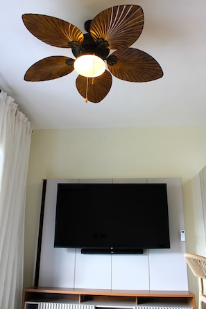 Ein Deckenventilator mit Leuchte und ein Flachbildfernseher an der Wand.