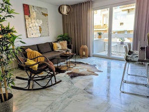Uma sala de estar com sofá, poltrona de balanço, mesa de centro e tapete.