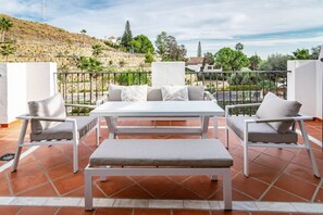 A terrace with a white table and two chairs, a bench, and a view of a hillside. - PA18- Stunning flat, gym, indoor and outdoor pool (La Alquería-El Paraíso)