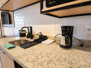 A kitchen with a granite countertop, a coffee maker, a knife block, and a sink. - SETIN 1903 (São Paulo)