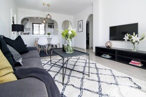A modern living room with a sofa, coffee table, and a flat-screen TV. - RDM - Stylish Holiday Apartment with Ocean Views (Mijas)