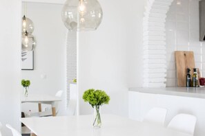 A modern kitchen with white cabinetry, a wooden cutting board, and a vase with green plants. - RDM - Stylish Holiday Apartment with Ocean Views (Mijas)