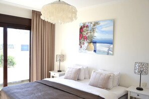 A hotel room with a bed, two bedside tables, a chandelier, a painting, and a view of the outdoors. - RSH14A - Penthouse with terrace and hot tub (Estepona)