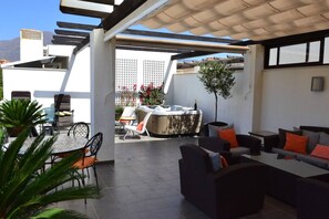 An outdoor patio area with a hot tub, seating arrangements, and a view of the mountains. - RSH14A - Penthouse with terrace and hot tub (Estepona)