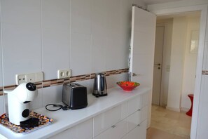 Ett kök med vita skåp, en brödrost, en vattenkokare och en skål på bänkskivan.