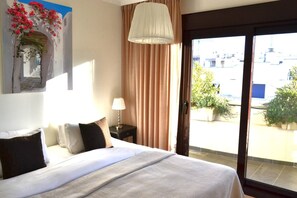 A hotel room with a bed, a nightstand, a lamp, a window with curtains, and a view of the outside. - RSH14A - Penthouse with terrace and hot tub (Estepona)
