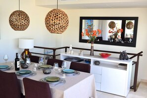 A dining area with a white table set for a meal, two hanging woven light fixtures, a white cabinet with a mirror above, and a vase with orange flowers on the cabinet. - RSH14A - Penthouse with terrace and hot tub (Estepona)