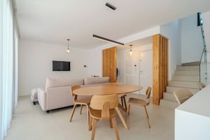 Ein modernes Wohnzimmer mit einem runden Holztisch, einem beigen Sofa und Holzstühlen.