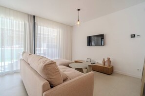 Ein modernes Wohnzimmer mit einer Couch, einem Couchtisch und einem flachbildfernseher an der Wand.