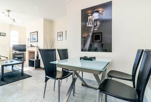 Un comedor moderno con una mesa de vidrio, sillas negras y un cuadro abstracto grande en la pared.