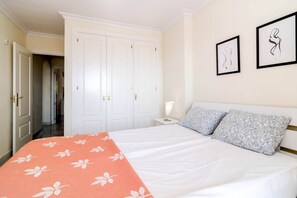 A hotel room with a bed, a nightstand, a lamp, a wardrobe, and two framed pictures on the wall. - SAA- Comfortable Apartment near Puerto Banus (Marbella)
