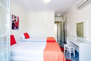 Ein Hotelzimmer mit zwei Betten, einem kleinen Tisch, einem Spiegel und einem Bild an der Wand.