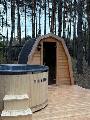 Una cabana de fusta amb banyera d'hidromassatge i terrassa.