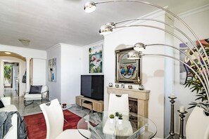 A modern living room with a glass dining table, a fireplace, and a television. - SAA2- comfortable apartment Puerto banus (Marbella)