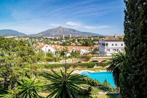 A residential area with a pool, surrounded by greenery and buildings, with a mountain in the background. - SAT2 - Modern 2 bedroom apartment with ocean view (Marbella)