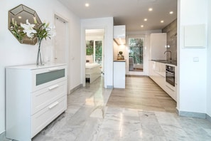 A modern kitchen with white cabinetry, a hexagonal mirror, and a vase with flowers. - SAT2 - Modern 2 bedroom apartment with ocean view (Marbella)