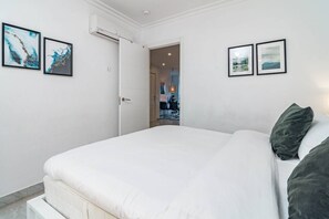 A bedroom with a bed, a door leading to a bathroom, and two framed pictures on the wall. - SAT2 - Modern 2 bedroom apartment with ocean view (Marbella)