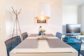A dining area with a table, chairs, a vase with flowers, a television, and a lamp. - SAT2 - Modern 2 bedroom apartment with ocean view (Marbella)