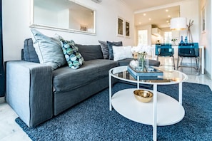 A modern living room with a grey sofa, a round coffee table, and a blue rug. - SAT2 - Modern 2 bedroom apartment with ocean view (Marbella)