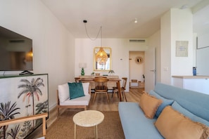 A modern living room with a sofa, a dining table, and a TV. - New modern apt, rooftop pool, Estepona - zaga3c (Estepona)