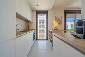 A modern kitchen with a built-in oven, a sink, and a window overlooking a balcony. - New modern apt, rooftop pool, Estepona - zaga3c (Estepona)