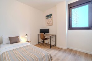 A bedroom with a bed, a desk, a chair, a window, and a painting on the wall. - New modern apt, rooftop pool, Estepona - zaga3c (Estepona)