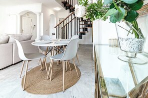 A modern dining area with a round table, white chairs, and a woven rug. - SAT25i Penthouse with Sea Views in Nueva Andalucia (Marbella)