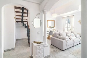 A modern living room with a staircase, a sofa set, a dining area, and a large mirror. - SAT25i Penthouse with Sea Views in Nueva Andalucia (Marbella)