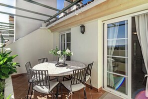 A round table with chairs, a vase of flowers, and a view through a glass door. - SAT25i Penthouse with Sea Views in Nueva Andalucia (Marbella)