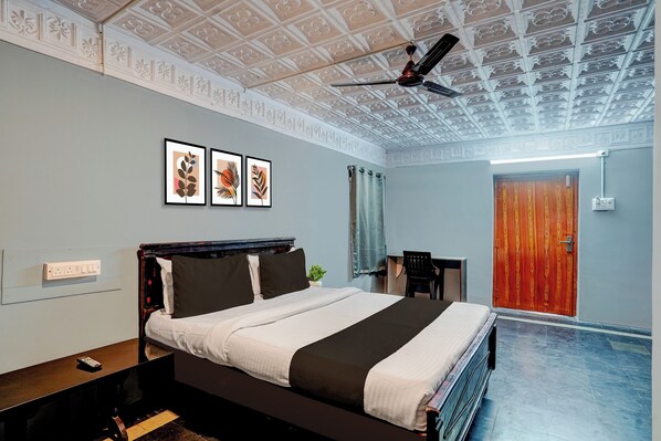 A bedroom with a bed, a ceiling fan, a desk, and a door. - Hotel O Vijayawada Bus Terminal (Vijayawada)