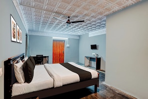 A bedroom with a bed, a desk, a chair, a television, and a door. - Hotel O Vijayawada Bus Terminal (Vijayawada)