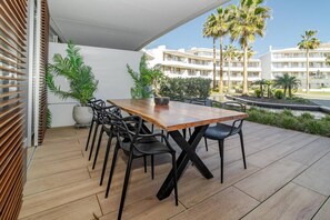 A wooden table with chairs on a balcony with a view of palm trees and a hotel building. - TE- Luxury resort, front line beach, families only (La Gaspara)