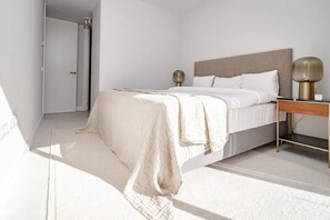 Une chambre à coucher avec un lit, une table de chevet, une lampe et une porte.