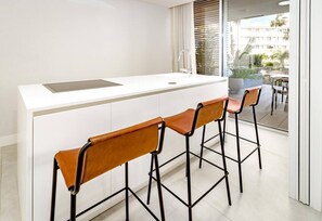 A modern kitchen with a white countertop, a built-in sink, and three bar stools with leather seats. - TE- Luxury resort, front line beach, families only (La Gaspara)